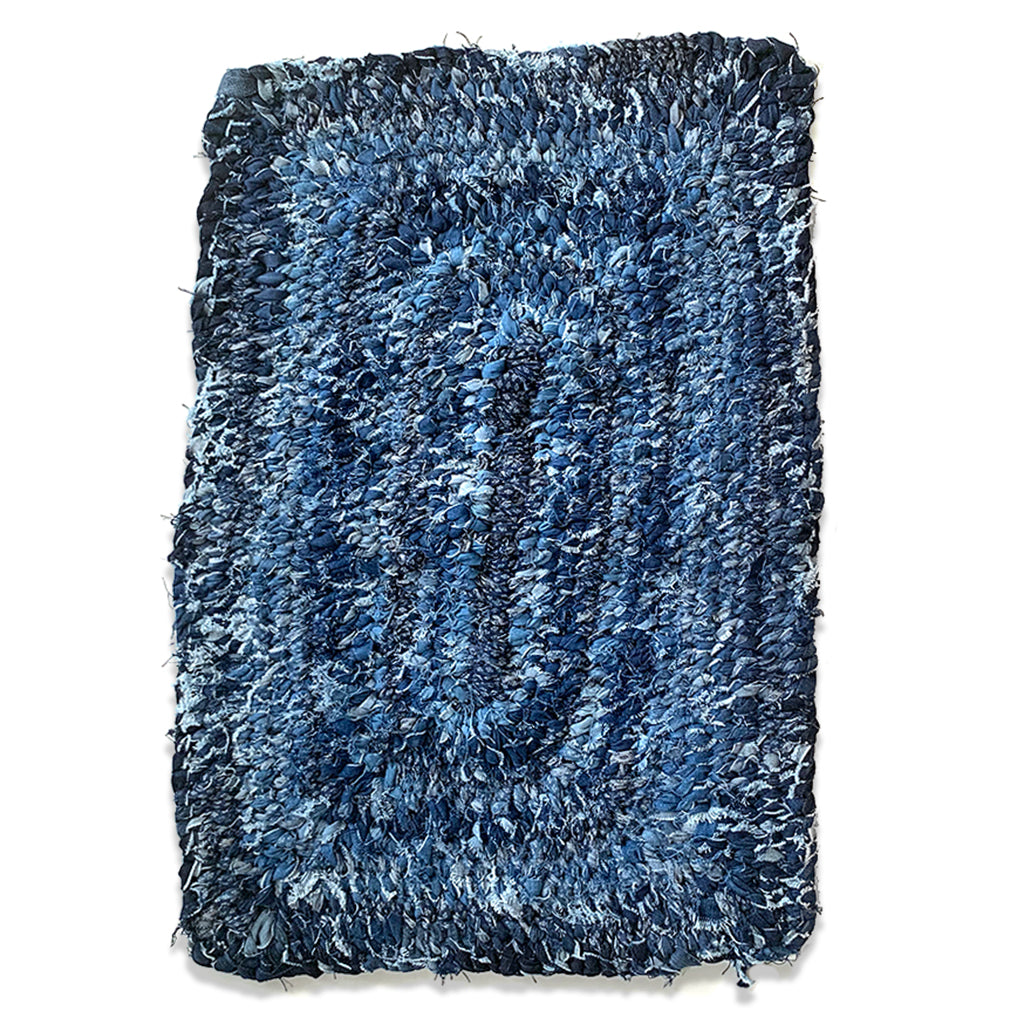 Hand Woven Upcycled Denim "Amish Knot" Rug. Rectangular shaped with different rows of varied coloured indigo.  