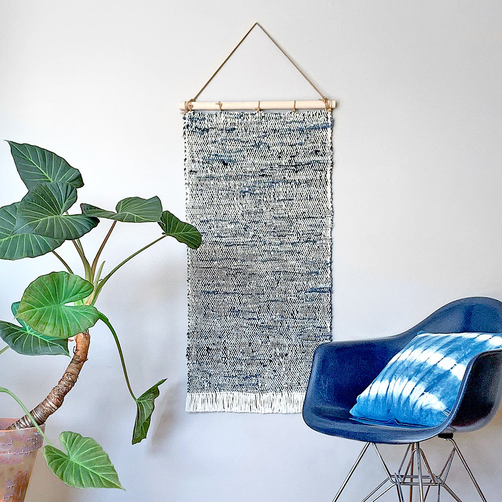 Hand Woven Upcycled Denim Tapestry on a wooden beam with frayed tasseled edges in white