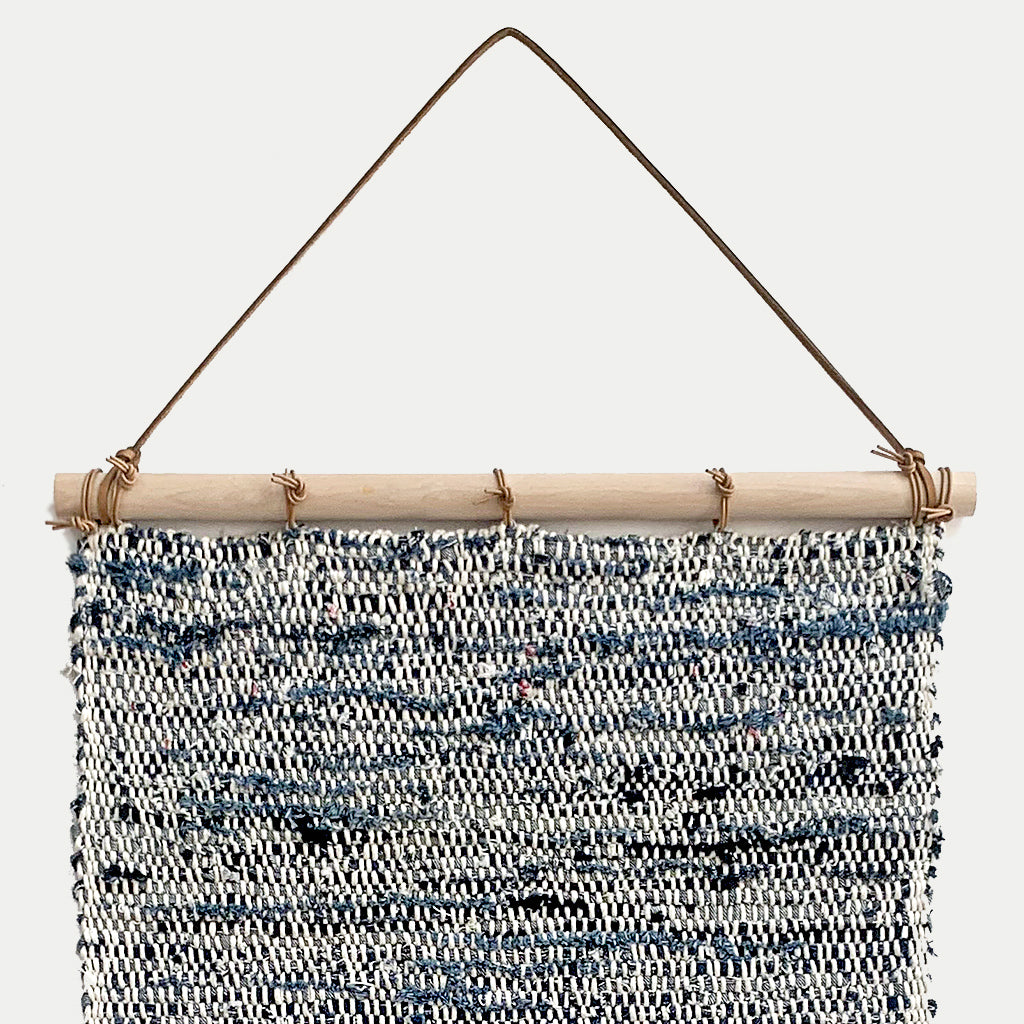 Hand Woven Upcycled Denim Tapestry on a wooden beam with frayed tasseled edges in white